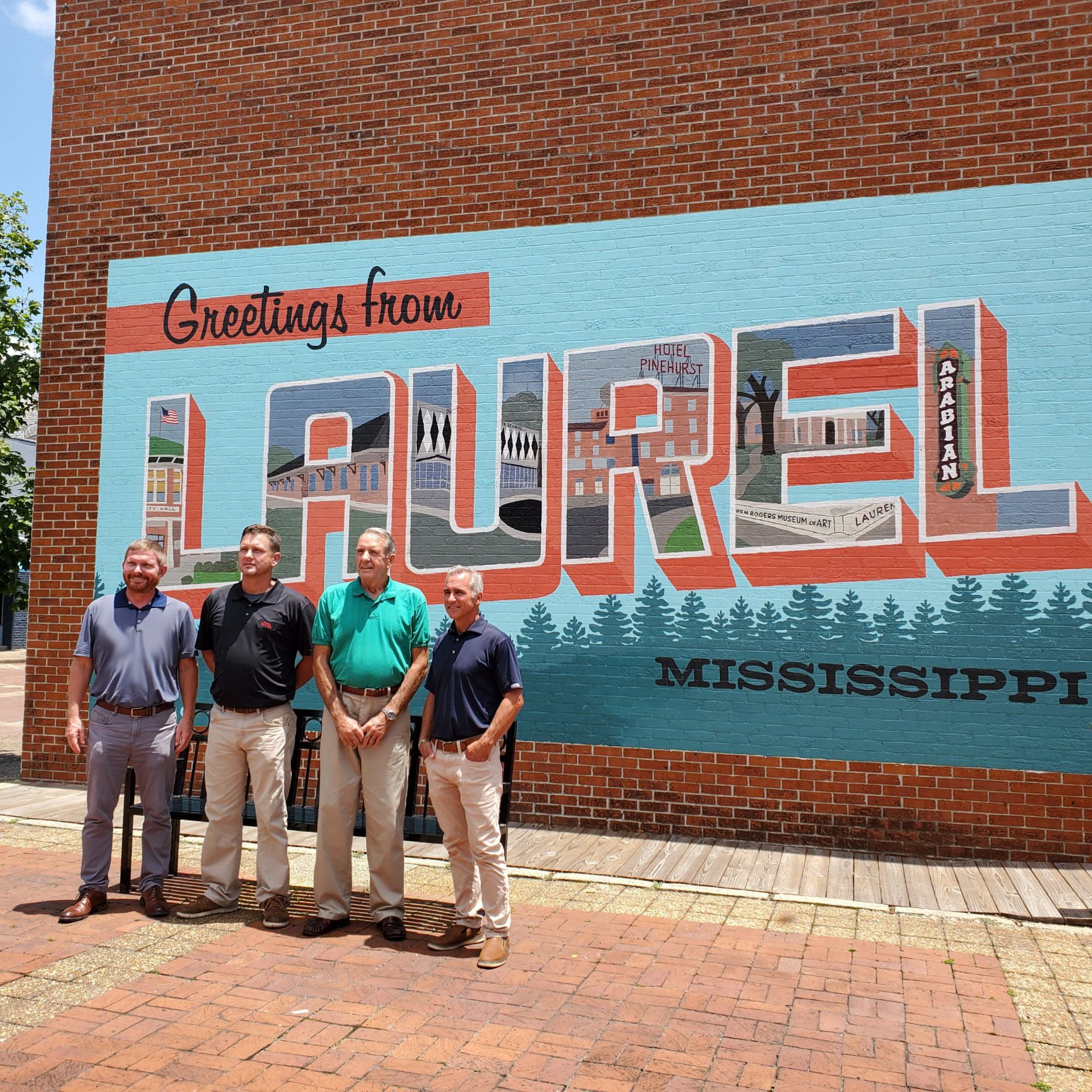 L-R: Director of Operations Joseph Hightower, American Fire President Brian Kenney with father Ralph Kenney, and VP of Business Development Chuck Reimel in front of the Downtown Laurel mural.